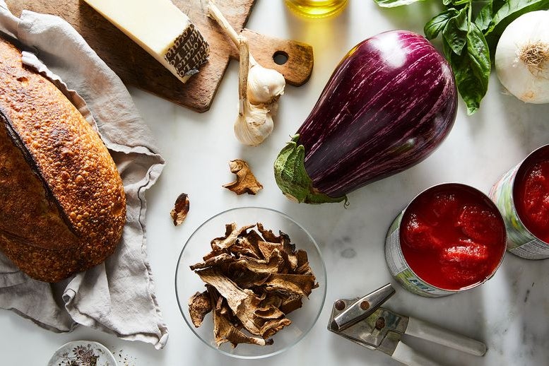 Eggplant, round loaf of bread, and tomato sauce in bowl.